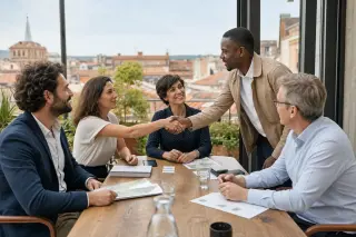 Business professionals exchanging contacts in a modern meeting room with southern French cityscape outside the window