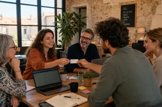 Entrepreneurs in a sunlit coworking space in southern France exchanging contacts around a table, relaxed and professional atmosphere.