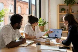 Entrepreneurs in a natural-light coworking space in Occitanie having a focused business discussion around a table.