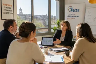 Business advisor meeting with entrepreneurs in a sunlit meeting room in southern France, discussing a business plan around a table.