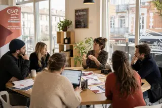 Entrepreneurs and a CMA advisor discuss paperwork in a modern coworking space with natural light and subtle southern France decor.