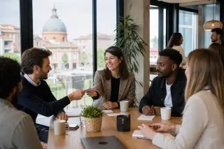 Entrepreneurs in a modern coworking space in southern France engaged in a business networking discussion with natural light and an Occitanie urban backdrop.