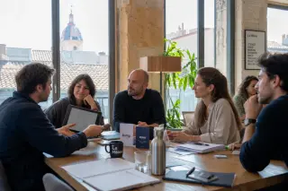 Coworking space in Occitanie with entrepreneurs collaborating at a table in natural light, project discussion in progress.